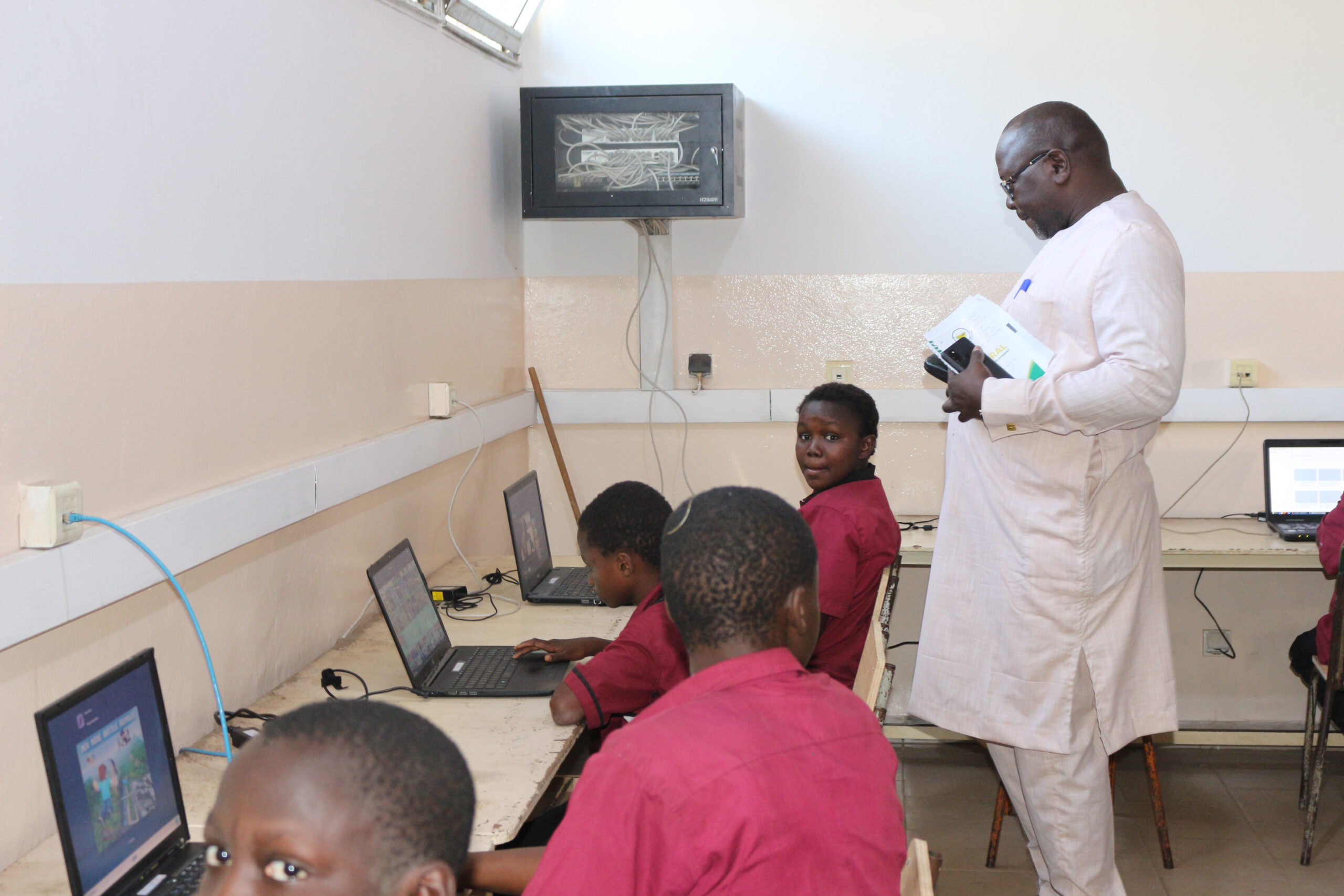 Der Vertreter des Schulministeriums beobachtet Schulkinder am Tag der Einweihung des Computerraumes
